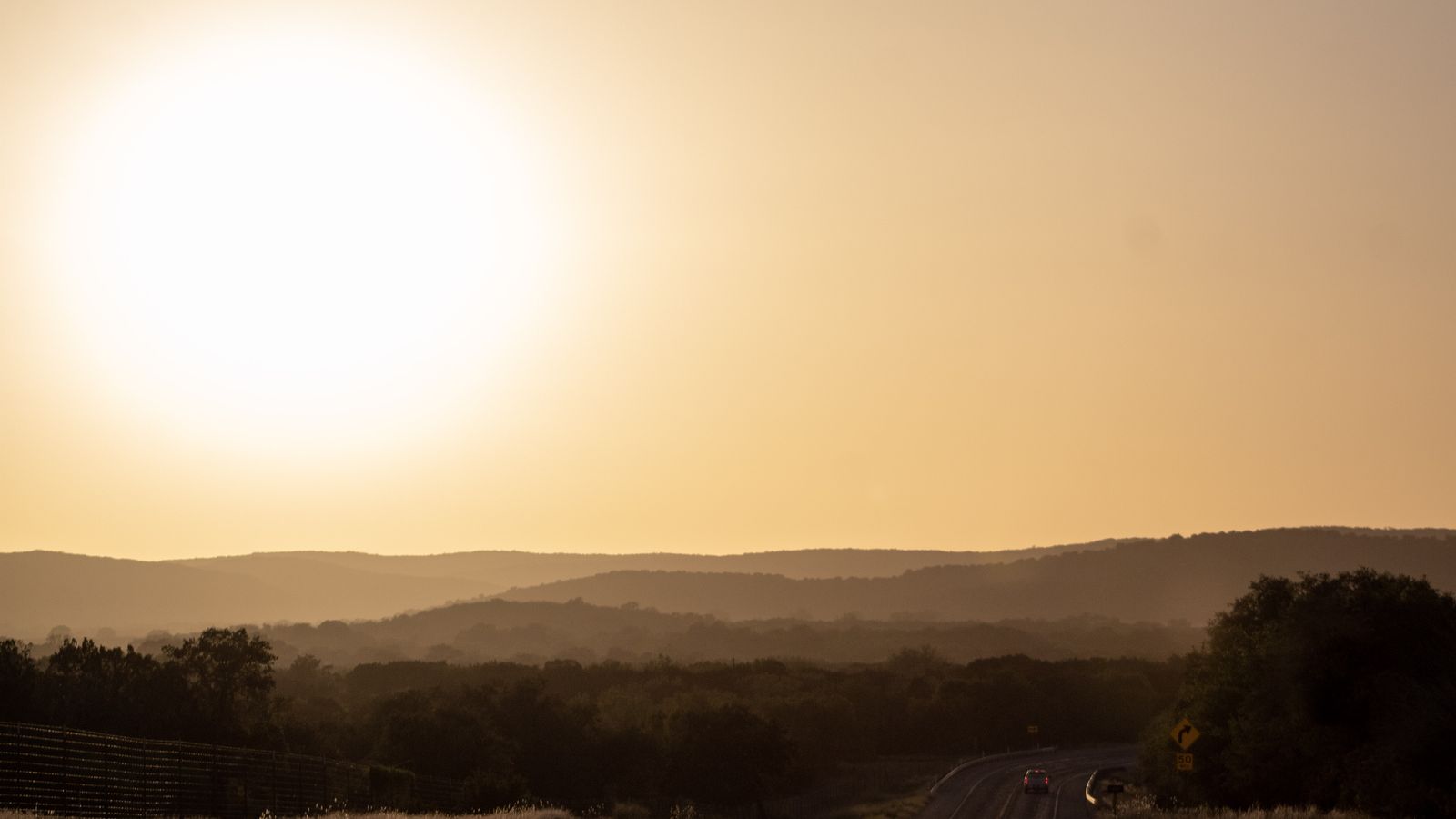 Off duty: a big low sun over hazy rolling hills, soft golden light.